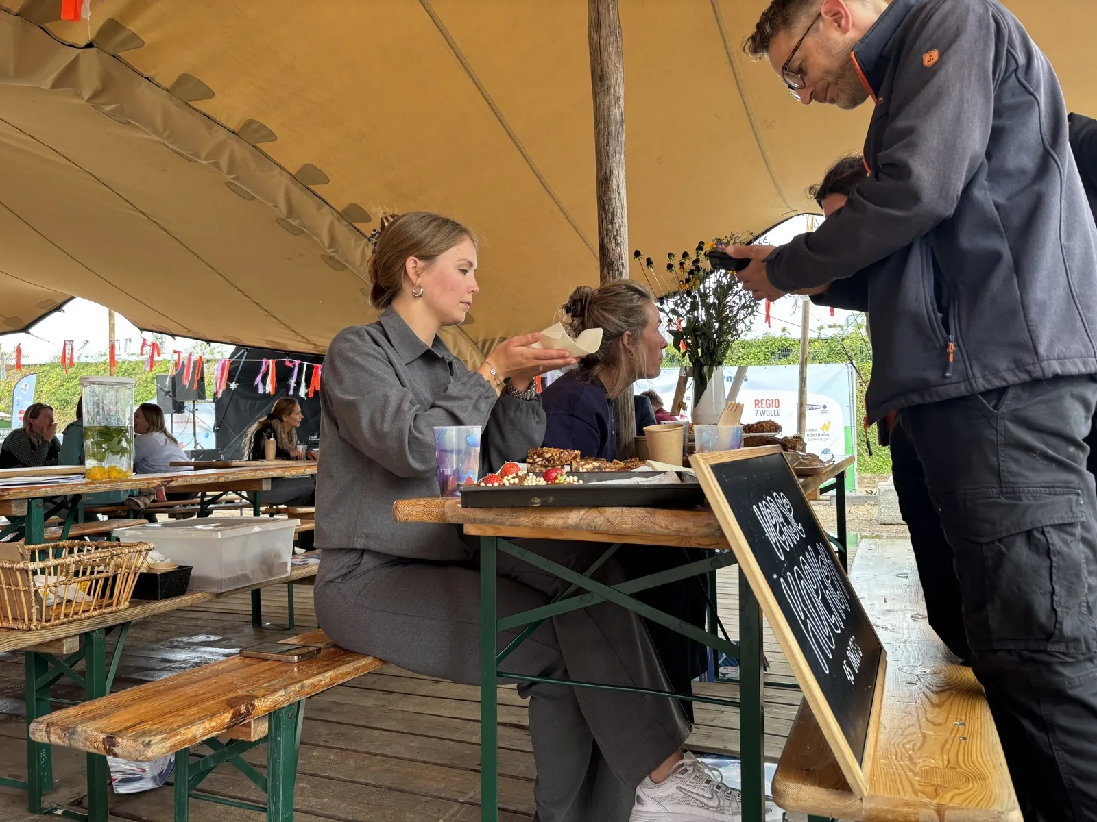 Een bezoeker rekent met de telefoon af bij een kraam op een buitenevenement