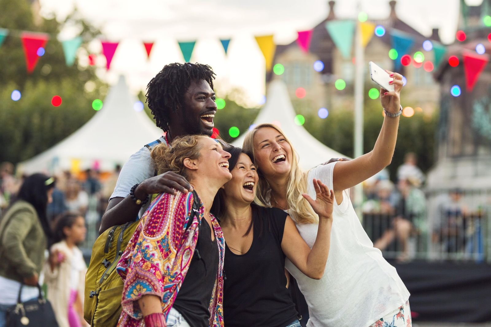 Vrienden maken een selfie op een zomerfestival met vlaggetjes en lichtjes