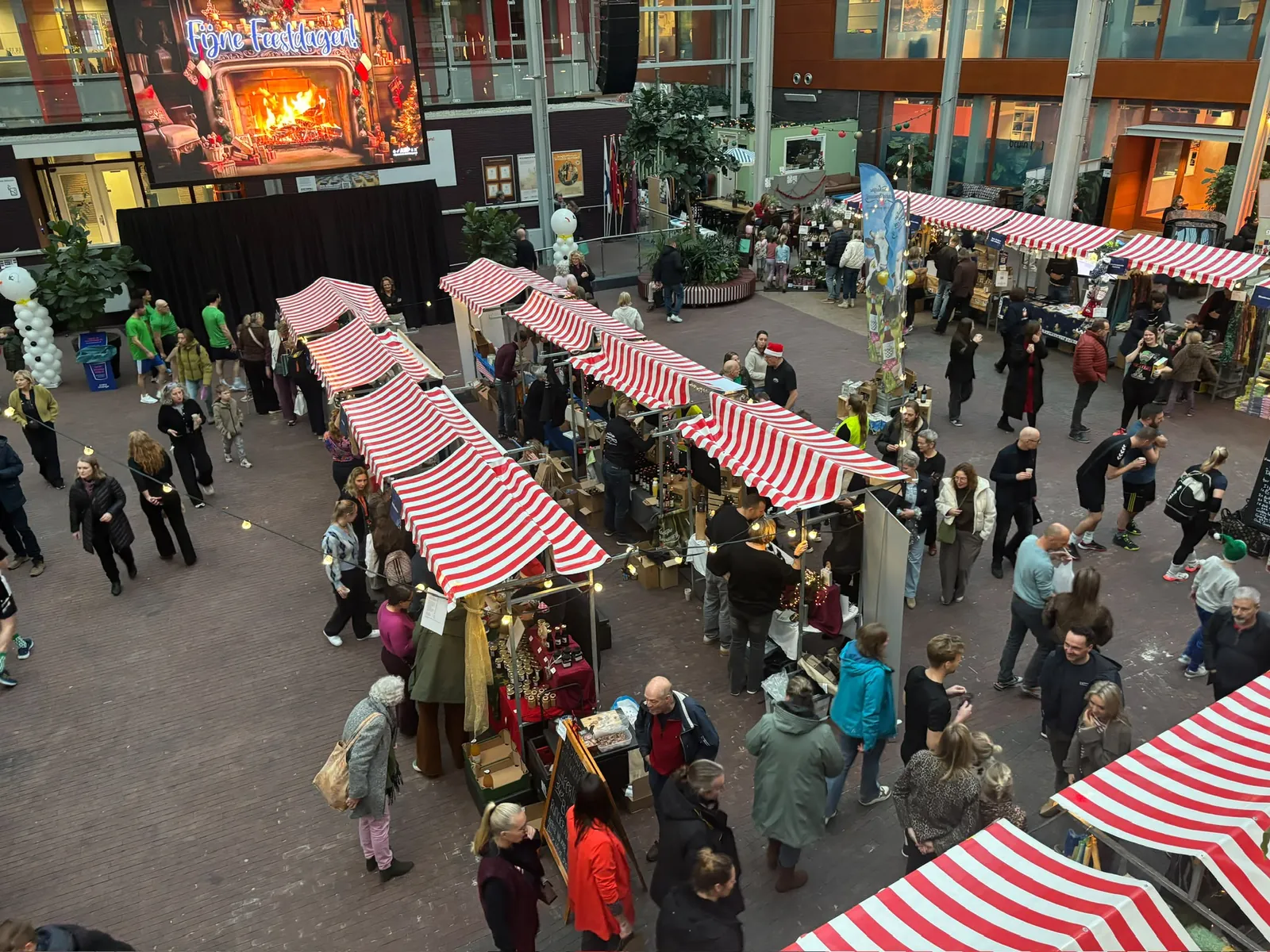 Drukke markt met kraampjes en honderden bezoekers, waar met digitaal tegoed wordt betaald